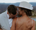 Couple embracing with scenic background in white hat