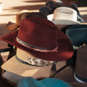 Stack of various hats including a red one with a feather and black band.