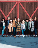 Group of people in hats posing in front of a wooden barn door