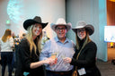 Three people wearing cowboy hats posing together at an event.