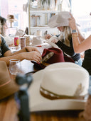People trying on hats in a store with various hats displayed.