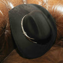 Black suede cowboy hat on leather couch