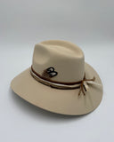Three-quarter view of ivory wool felt western hat with decorative element on the side and brown leather band by Gem Hats
