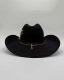 Back profile of black suede cowboy hat with curved brim, decorative band, and feather, Gem Hats Denver