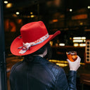 Person wearing a red hat and holding a drink in a bar setting