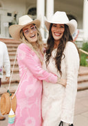 Two women wearing cowboy hats and smiling outdoors.