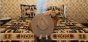 Person holding a cowboy hat in front of a patterned wall and bedspread.