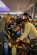Group of people gathered around a custom hat bar