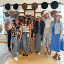 Group of people posing in front of a wall with hats